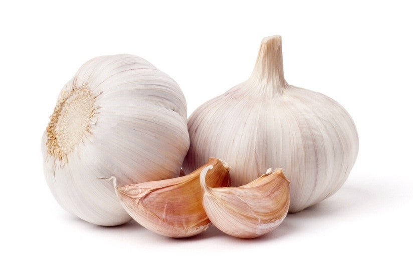 Two whole garlic bulbs sit beside two peeled garlic cloves, ready to add flavor to any dish.
