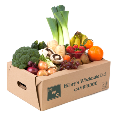 A cardboard box overflows with fresh produce, including broccoli, leeks, grapes, and oranges, showcasing a vibrant grocery delivery from Hilary's Wholesale Ltd.